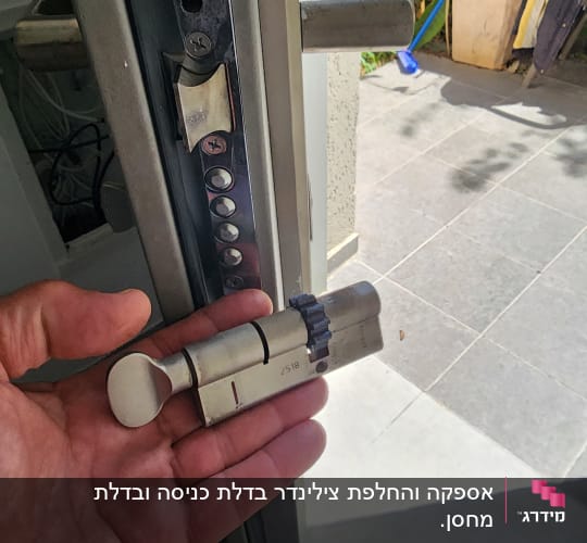 יד מחזיקה צילינדר מנעול ליד דלת פתוחה